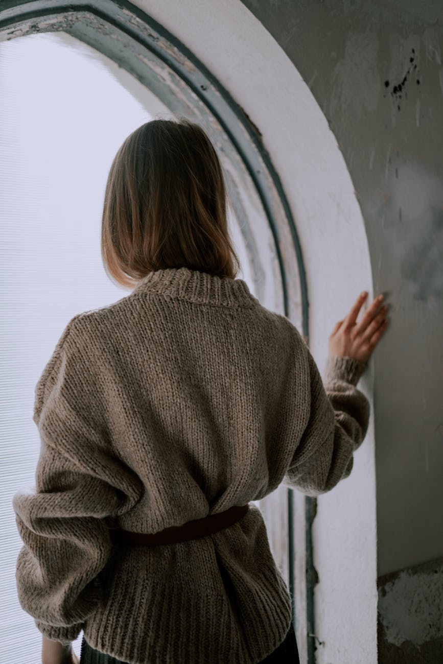 woman in oversized sweater standing in window