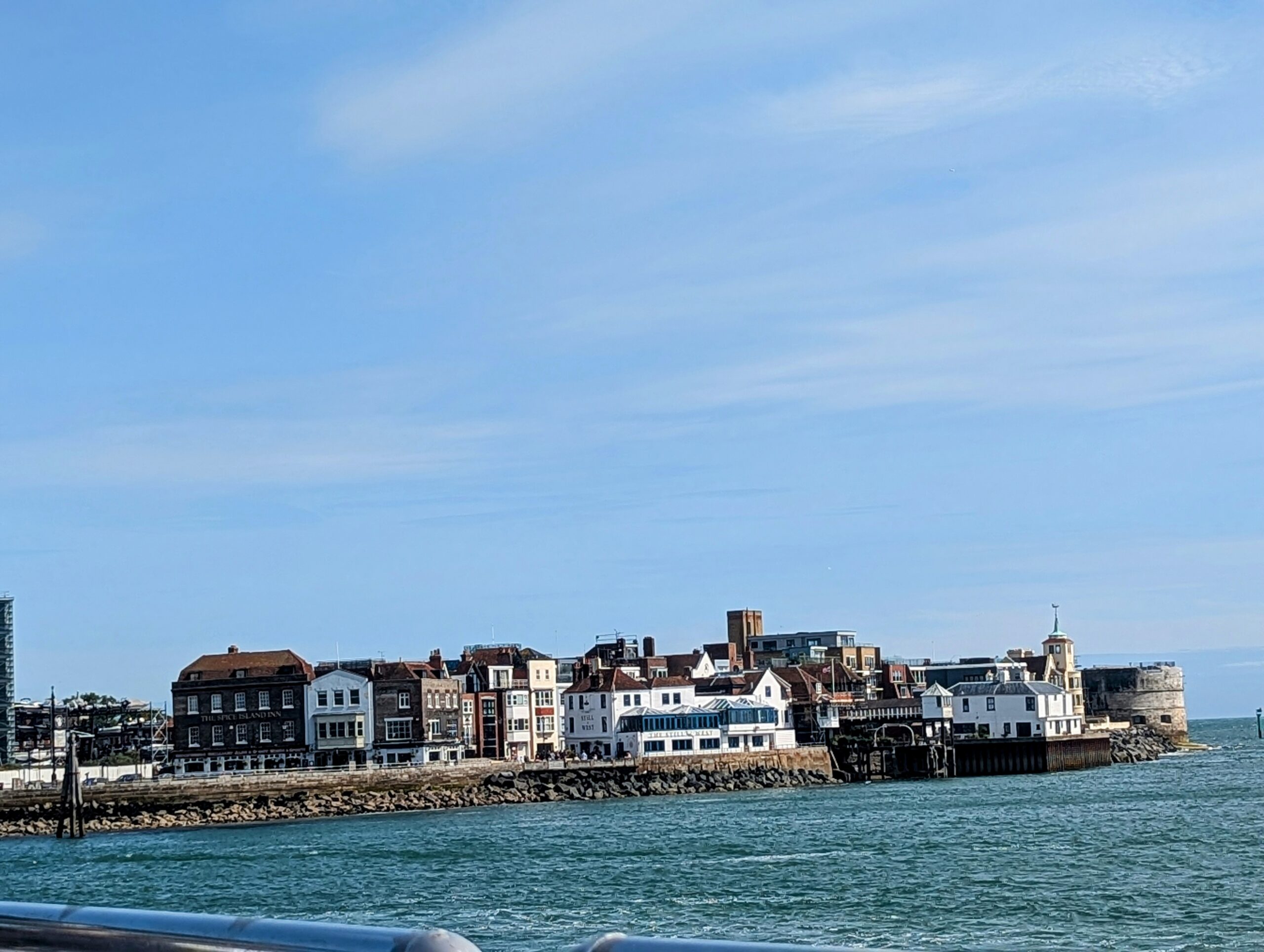A dorsal view of portmouth harbour from a boat on sea. Captures historic sites like the Round Tower & the Old Spice Inn