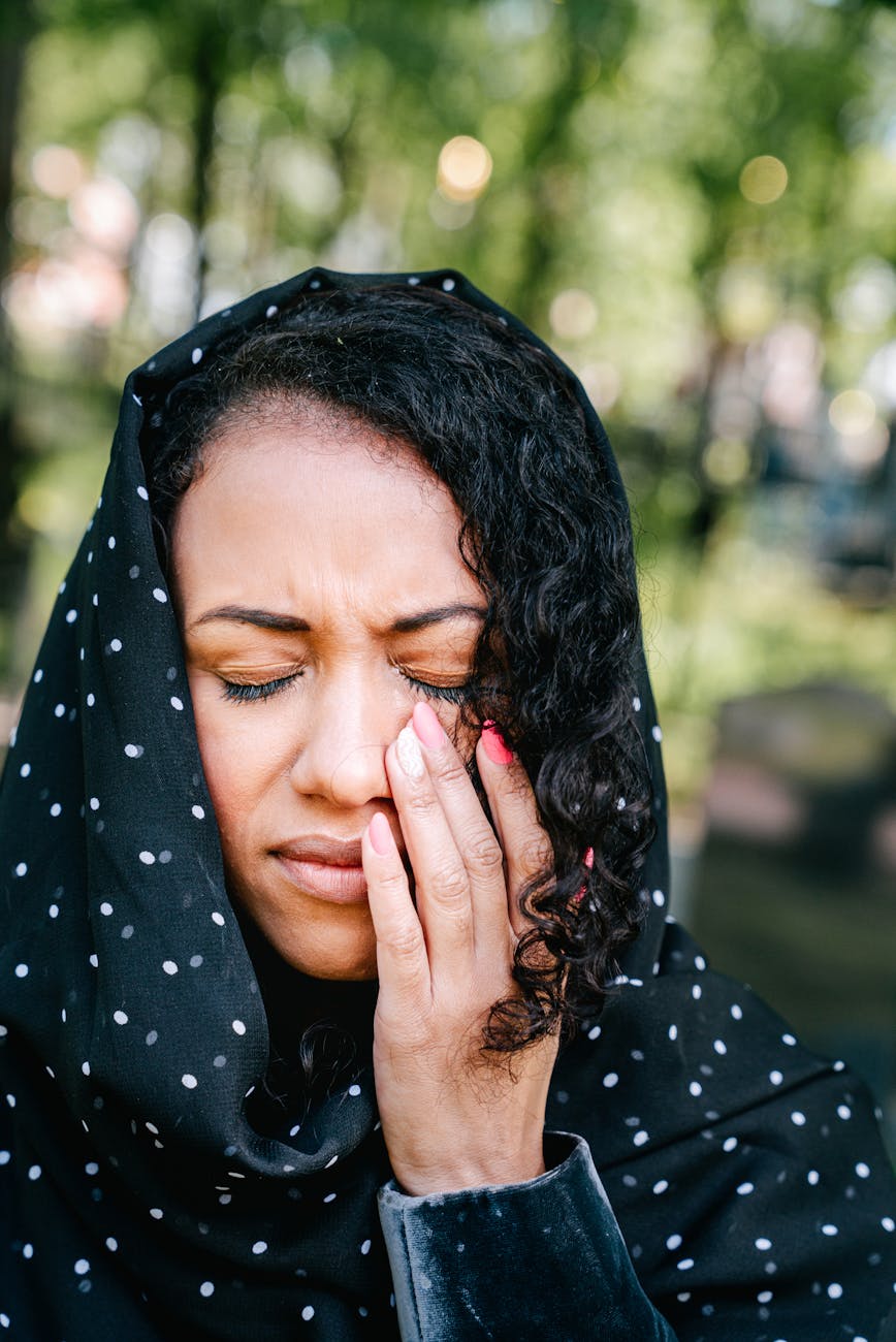 woman in black and white polka dot hijab crying